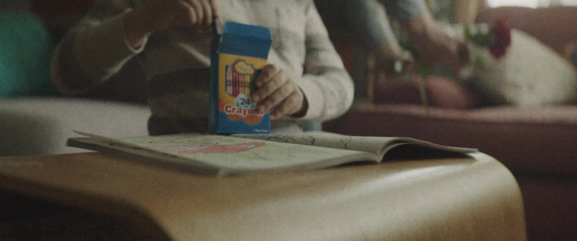 A child is holding crayons next to a coloring book