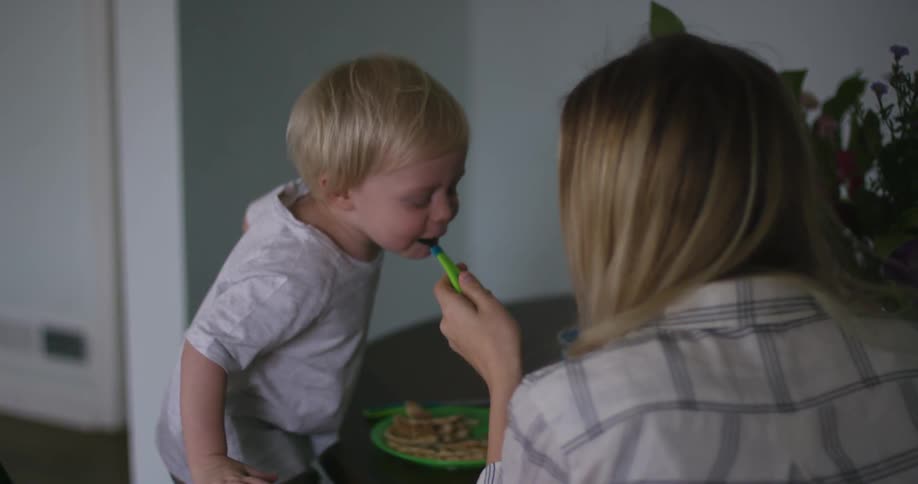 A woman feeds a boy with a fork