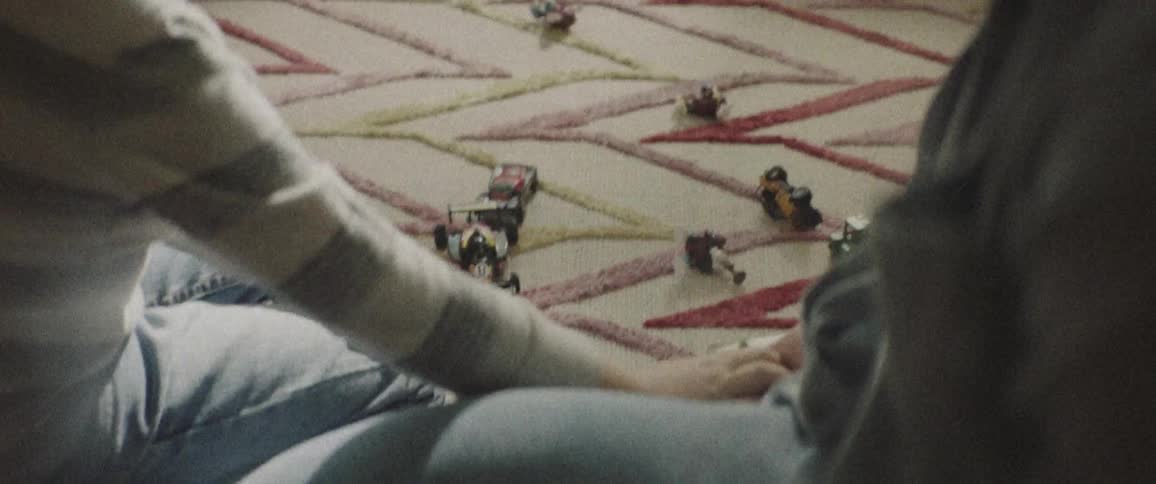 A man and a boy sitting on the living room floor playing with a toy truck