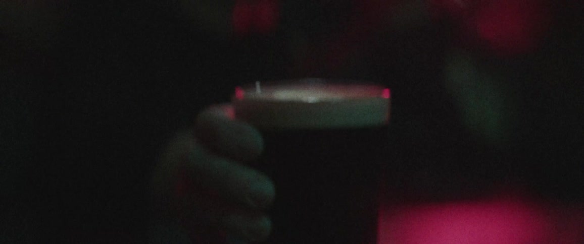 A woman picks up and drinks from a full glass of beer