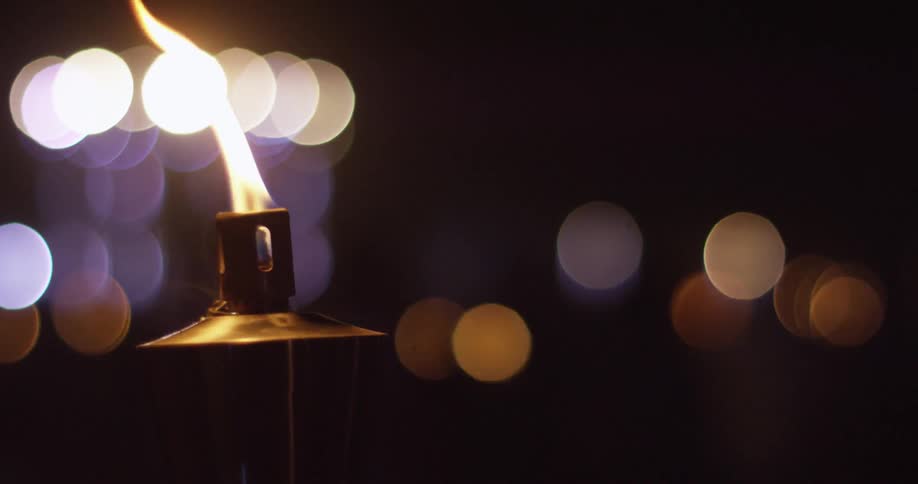 A flaming torch burns outside at night