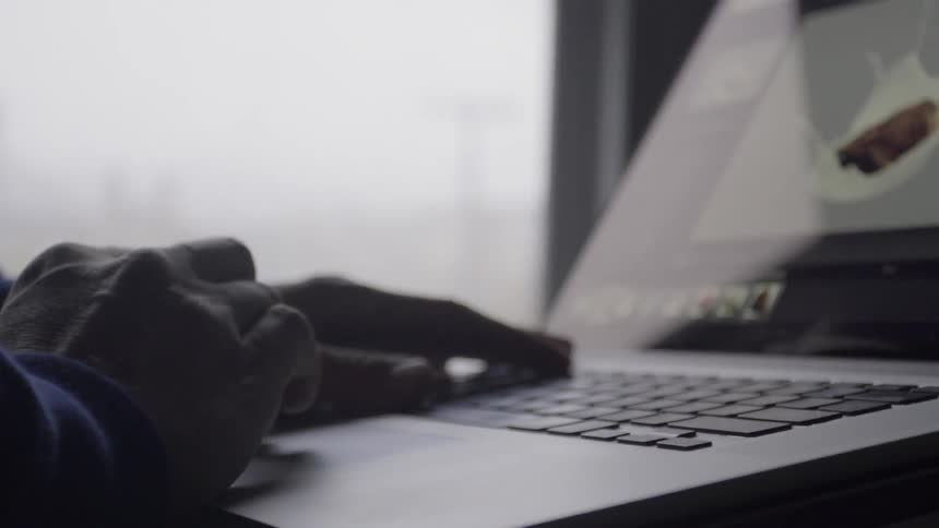 A person is working on their laptop in a dim room