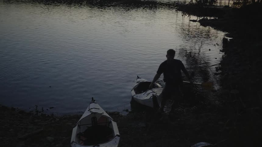 A man pulls his canoe from the lake