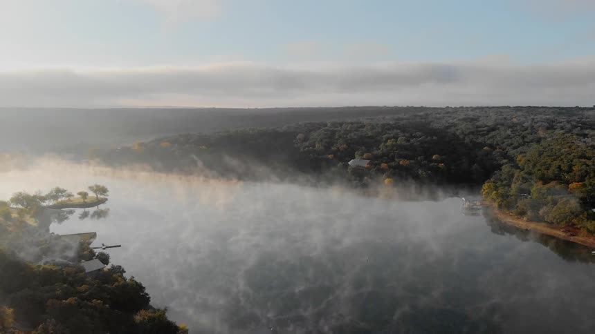 An aerial view of a foggy river at dawn