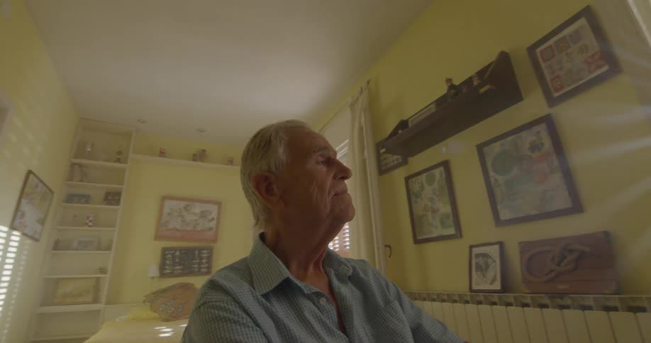 An elderly man looks out a window