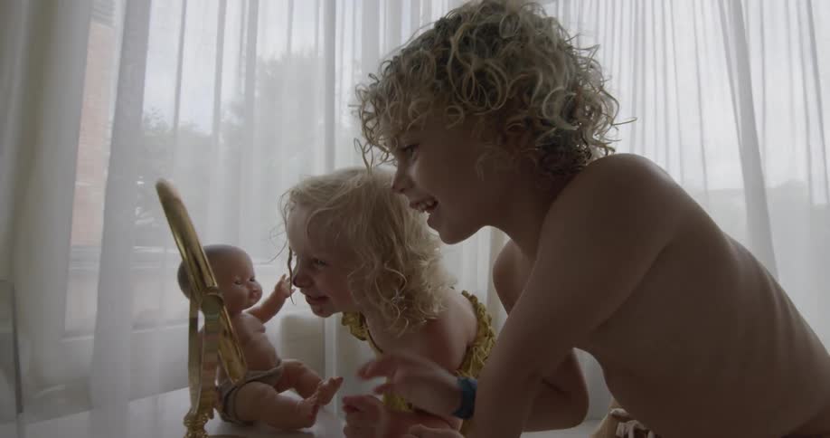 Two childrenplaying in a mirror