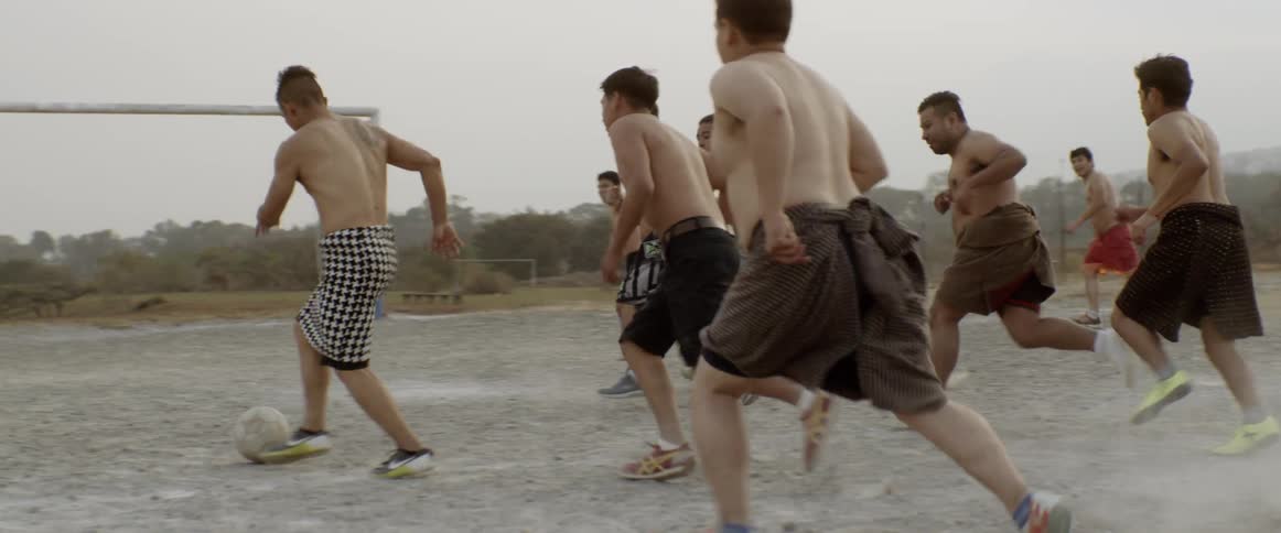 Man does a backflip as he plays soccer with other men