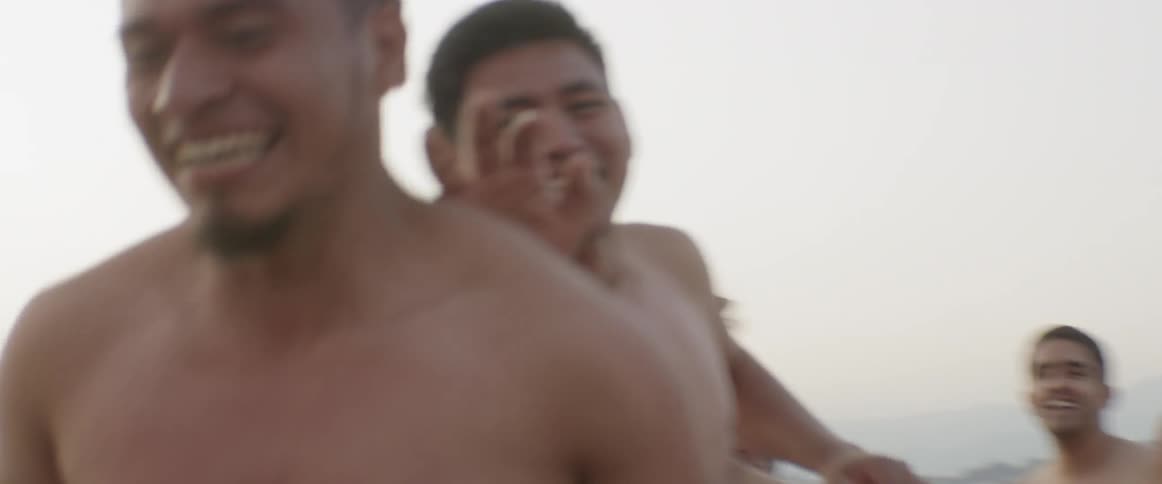A group of shirtless men hug each other in celebration
