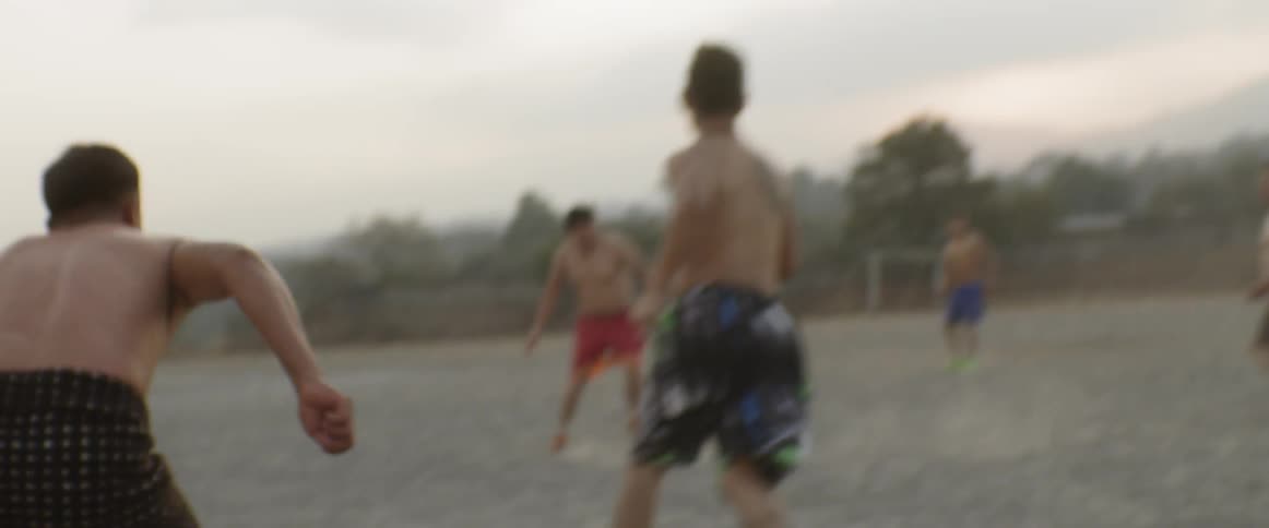 A group of shirtless man playing ball at the football field