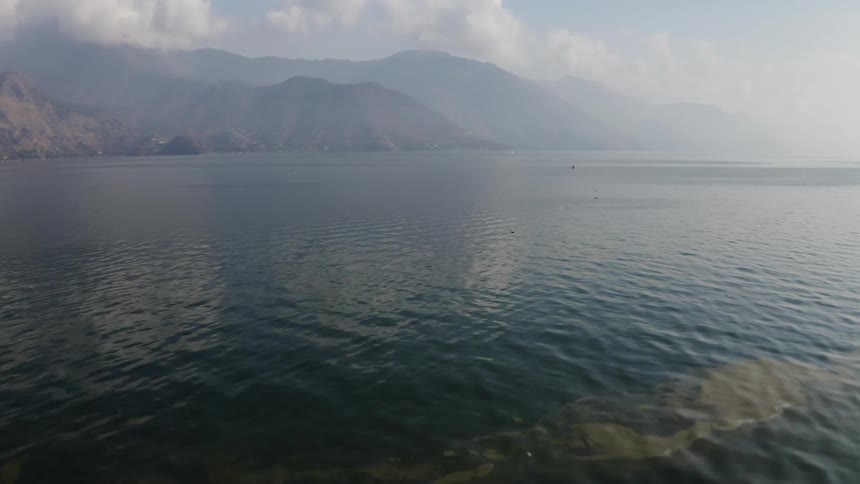 An ocean with mountains and the sky in the background