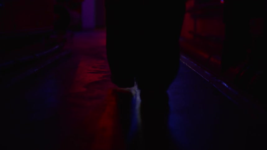 A man walking in the dark under neon light