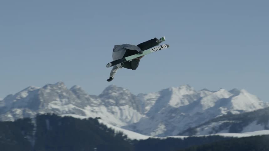 A man skiing jumps and flips over a bank