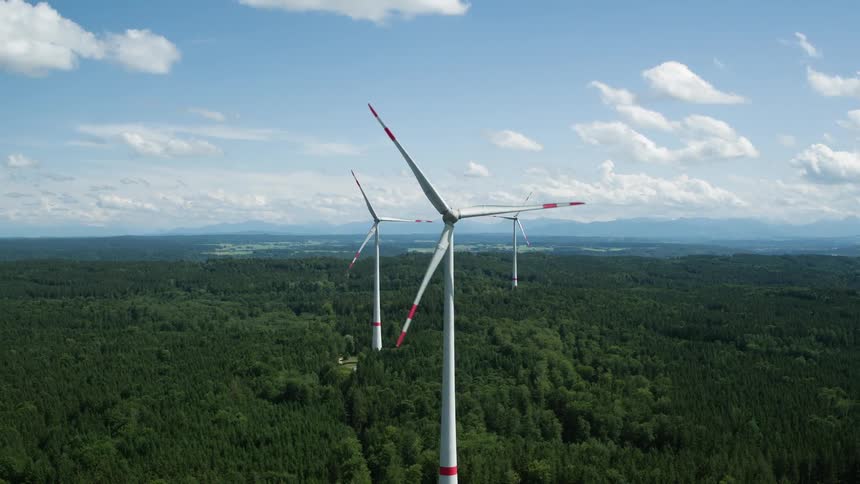 Wind turbines spinning over a forest