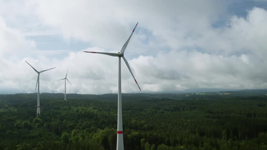 Wind turbines spinning over a forest