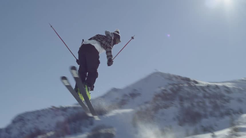 A person skiing off a ramp spinning 540 degrees in the air before landing backwards on the slope
