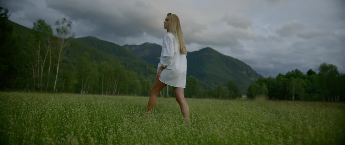A woman is walking in a grass field