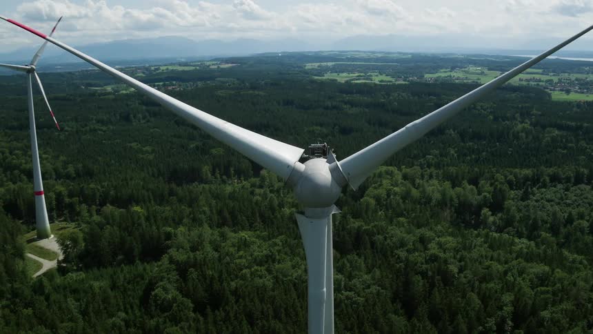 Workers servicing wind turbine on woodland at mid day