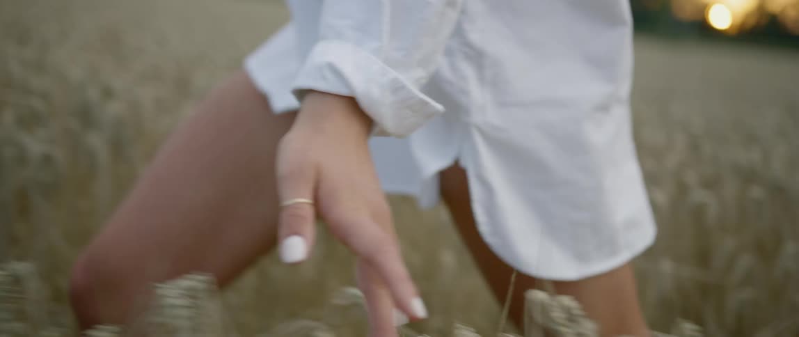 A woman in a dress shirt running through a field of tall grass