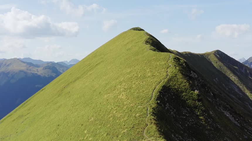 Vegetation covers mountain summit under cloudy blue sky