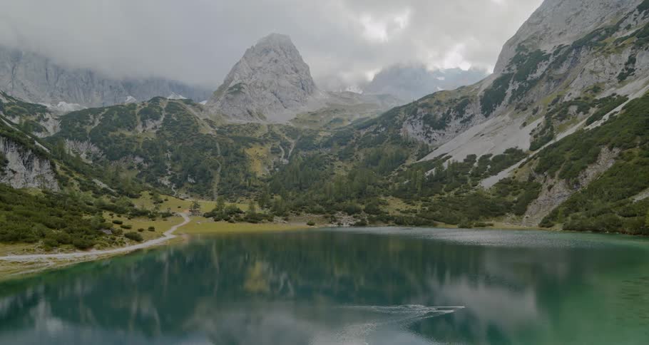 Aerial view of lake surrounded by pine trees and tall mountains