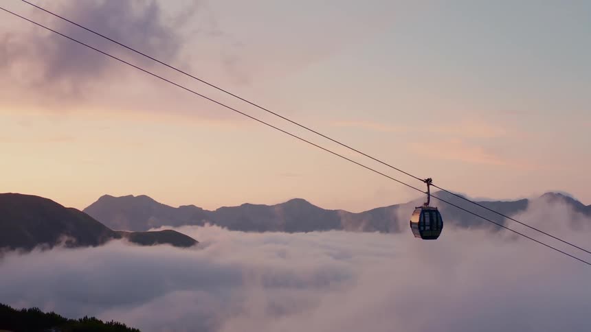 A gondola climbs above the clouds