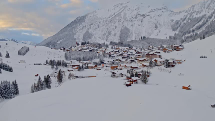 A town situated at the base of a mountain peak thats covered in snow