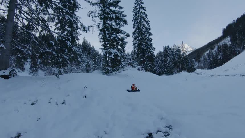 A drone flying near the ground in a snowy woodland
