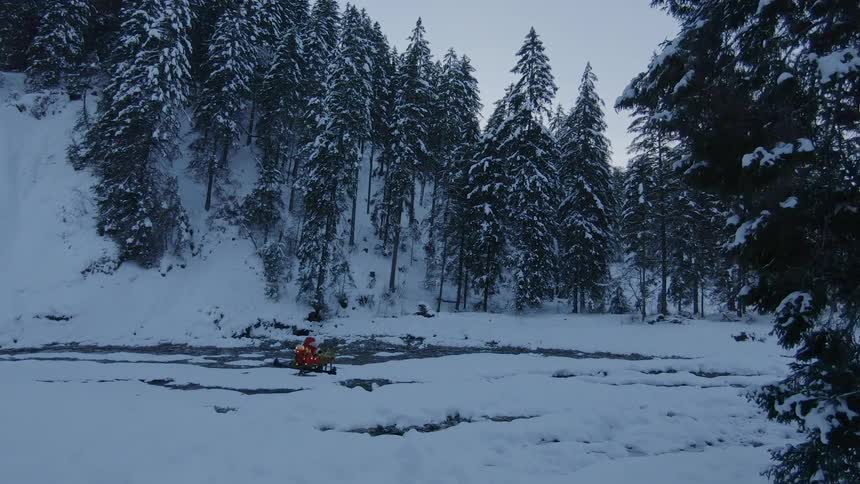 A forest covered in snow with a santa claus drone flying over the snow