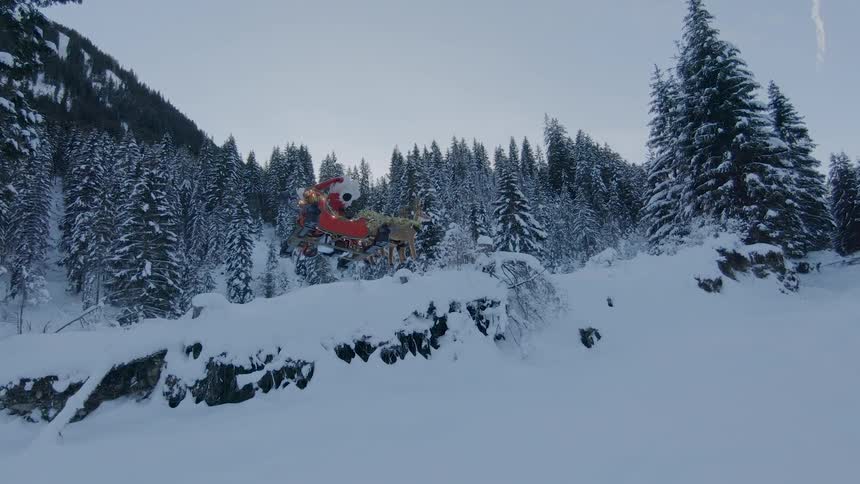 A remotely controlled drone with santa claus and reindeer figures mounted atop flying over a snowy landscape