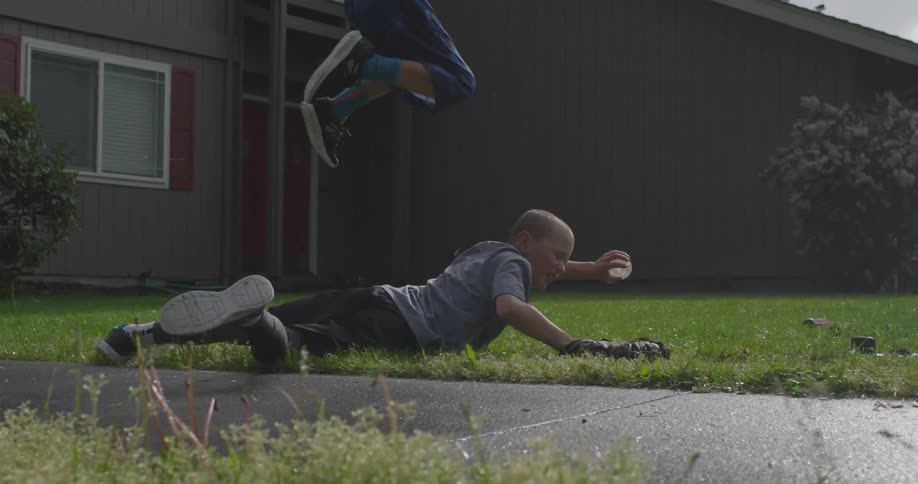 A child in a yellow shirt jumps over a child in a gray shirt
