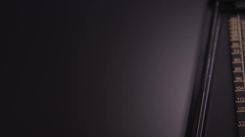 The arm of a metronome swings left and right