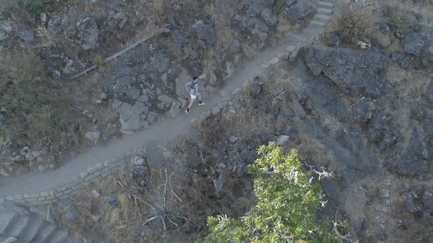 An aerial view of a man running at the mountain