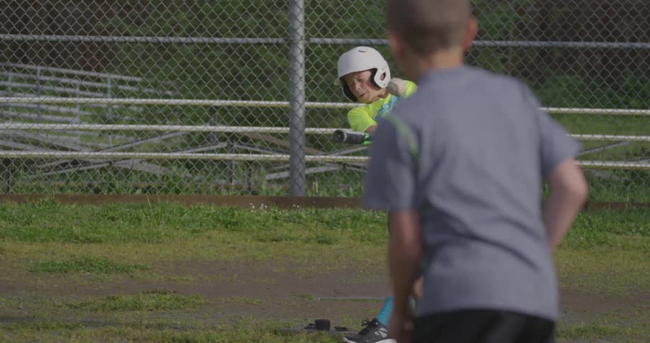 A boy hits a baseball pitched by another boy