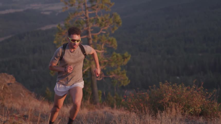 A man with glasses run toward a hill