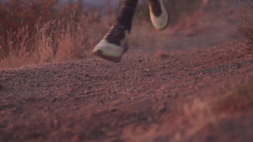 Man runs on the dirt road at sunset