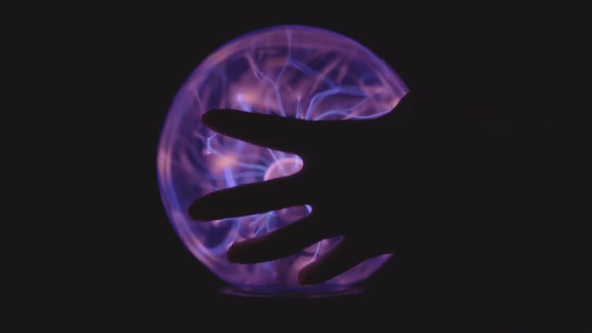 Hand touching a plasma ball creating laser bolts