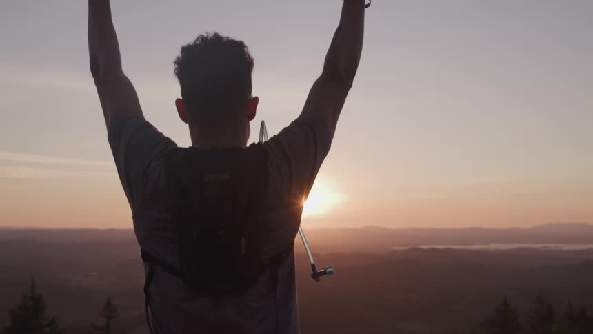 Silhouette of a man raising his hands up in celebration at sunrise