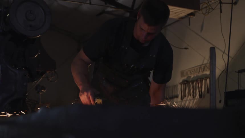 A person grinds metal in a workshop