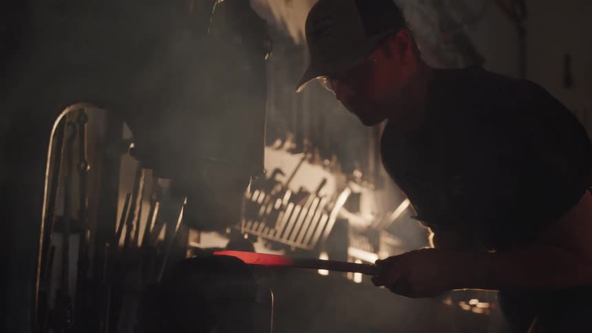 A man is working with hot metal by a machine