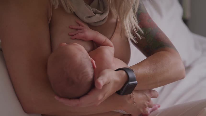A woman sitting in a bed breastfeeding a baby