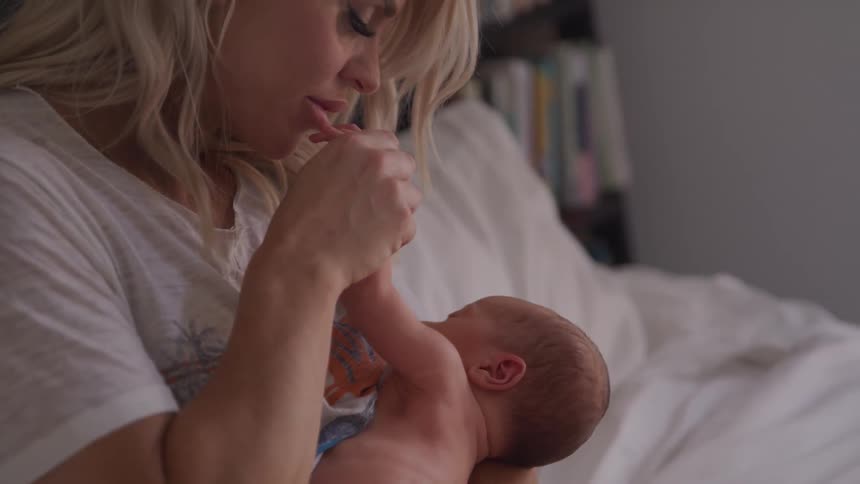A mother kisses the tiny hand of a newborn baby