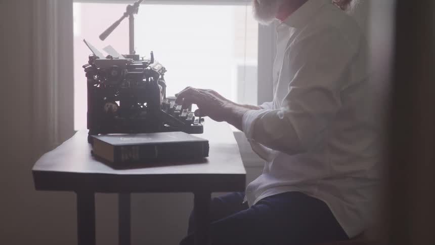 A man types on the old fashioned typewriter