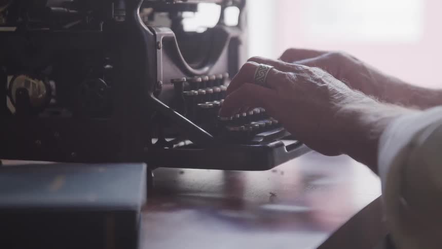 A man types on a vintage typewriter
