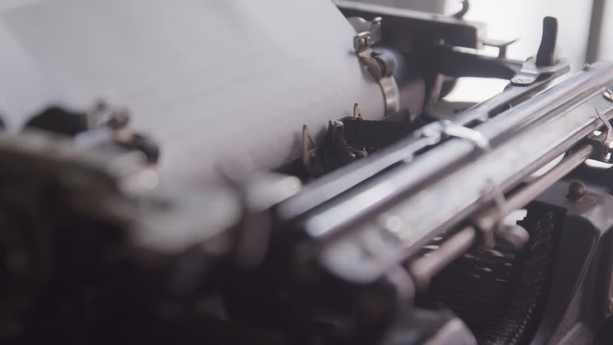 A typewriter ribbons moves up and down along the paper