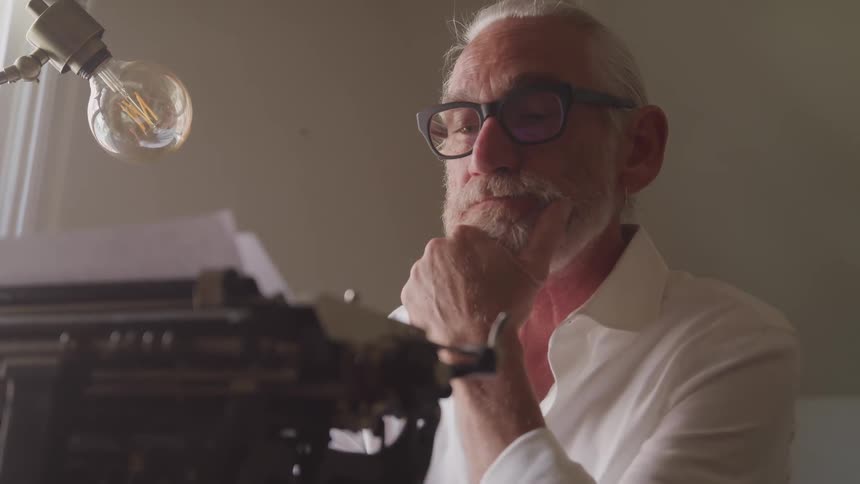 A man stares at a vintage typewriter reading whats on the page