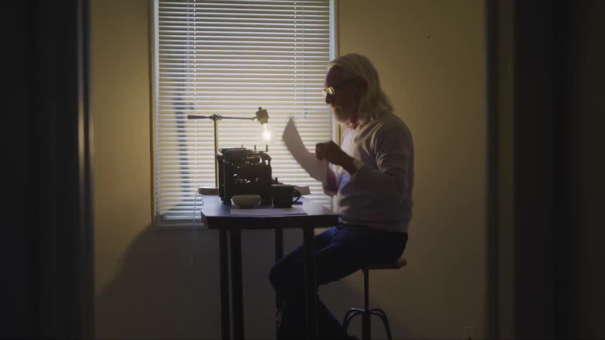 An elderly man replacing the paper in a typewriter