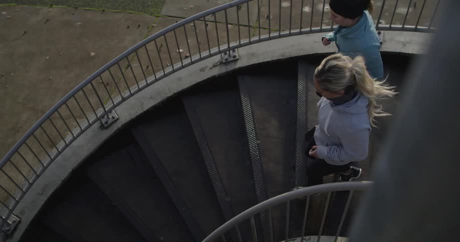 Women jog down a spiral staircase