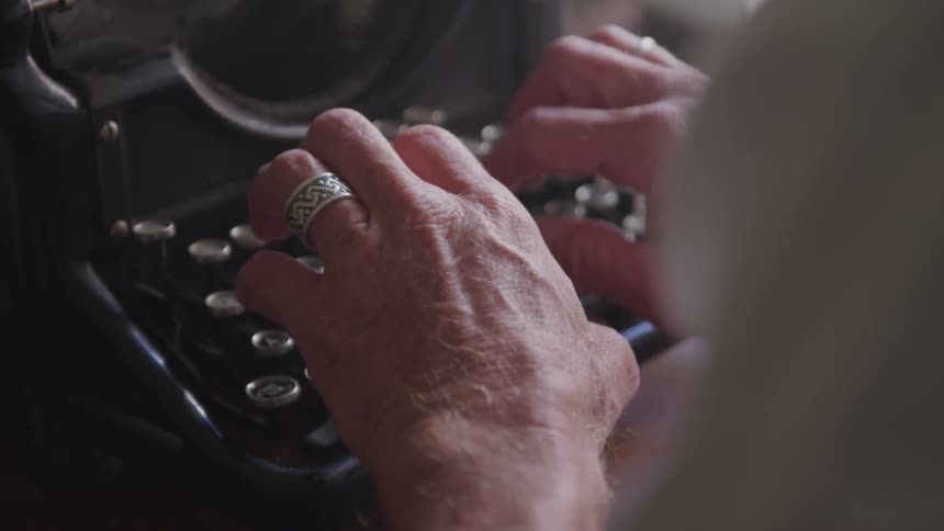 A man types on an antique typewriter
