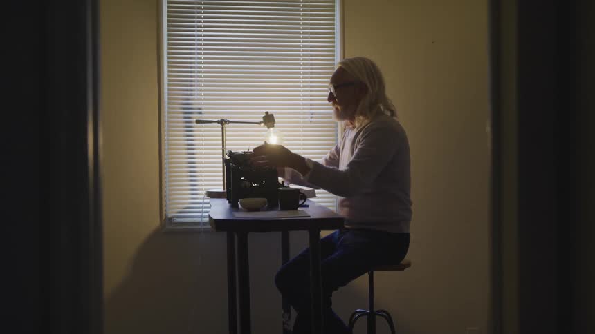 Man feeds in paper to manual typewriter