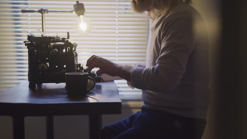 A man is typing on a typewriter indoors